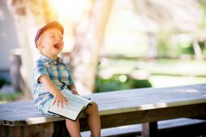 image of young boy laughing with book on his lap