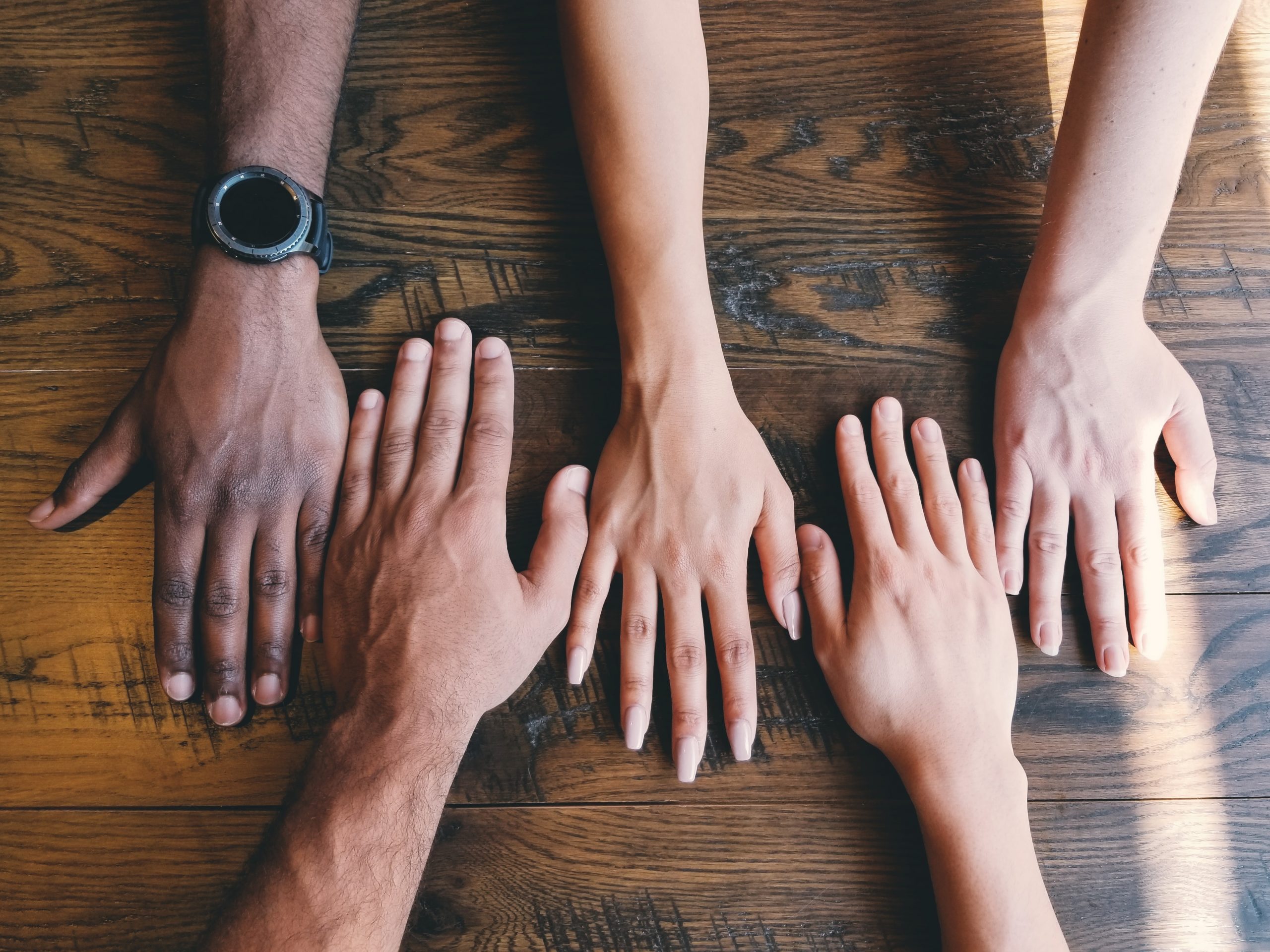 image of several hands down on a table