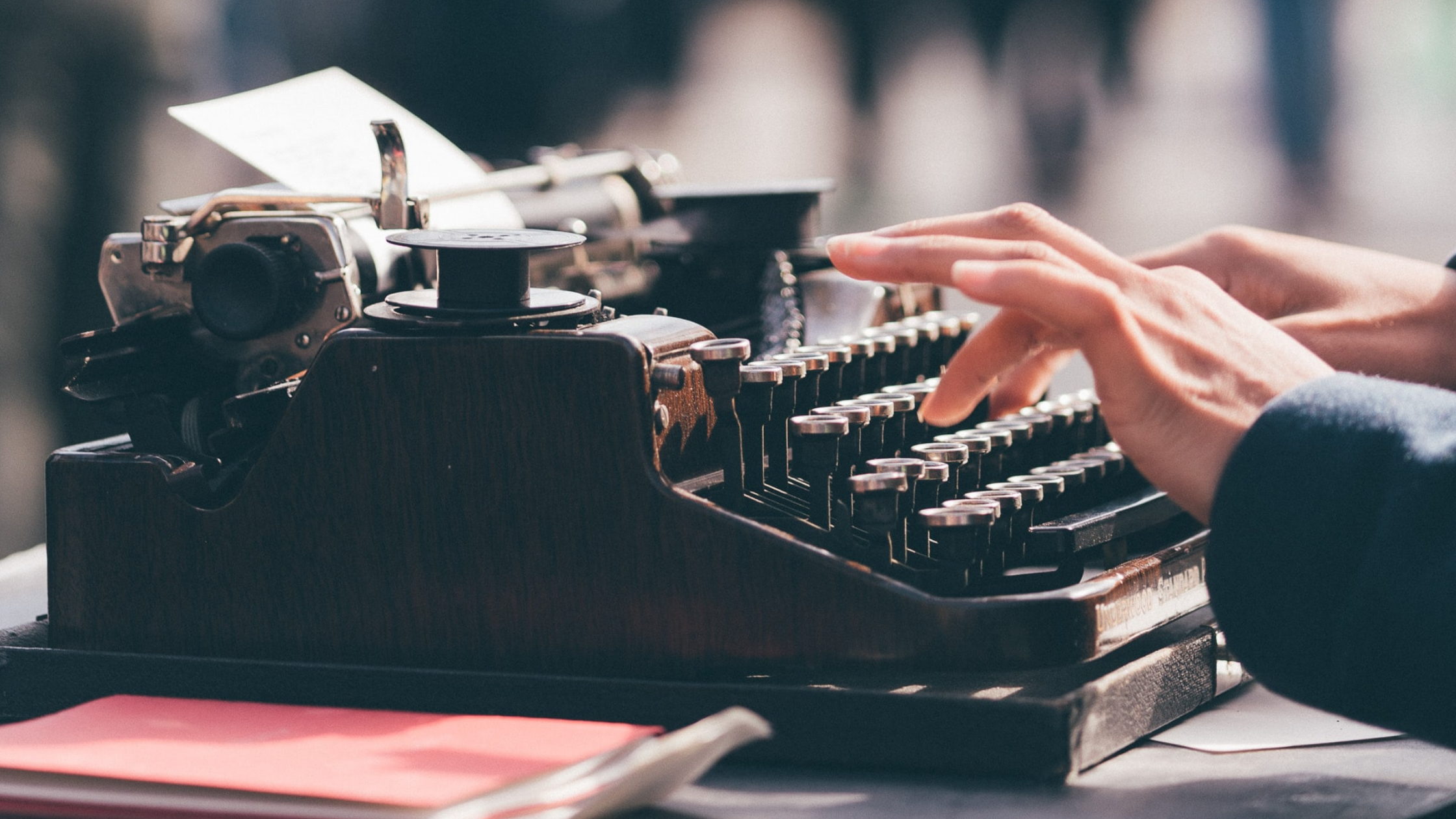 fingers poised to write over the keyboard of a black typewriter